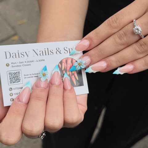 Client holding a Daisy Nails business card with pink and blue French tips