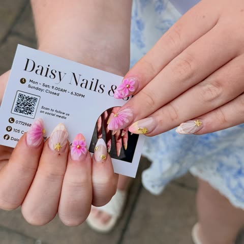 Client with pink 3D flower nails holding a business card