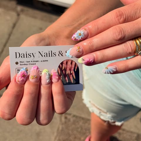 Client with summer floral nails holding a business card