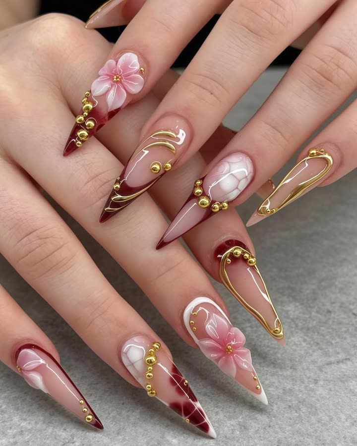 Stiletto nails with 3D pink blooms, burgundy and gold detail