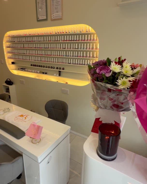 The reception desk with a lit display of gel polish colours and fresh flowers